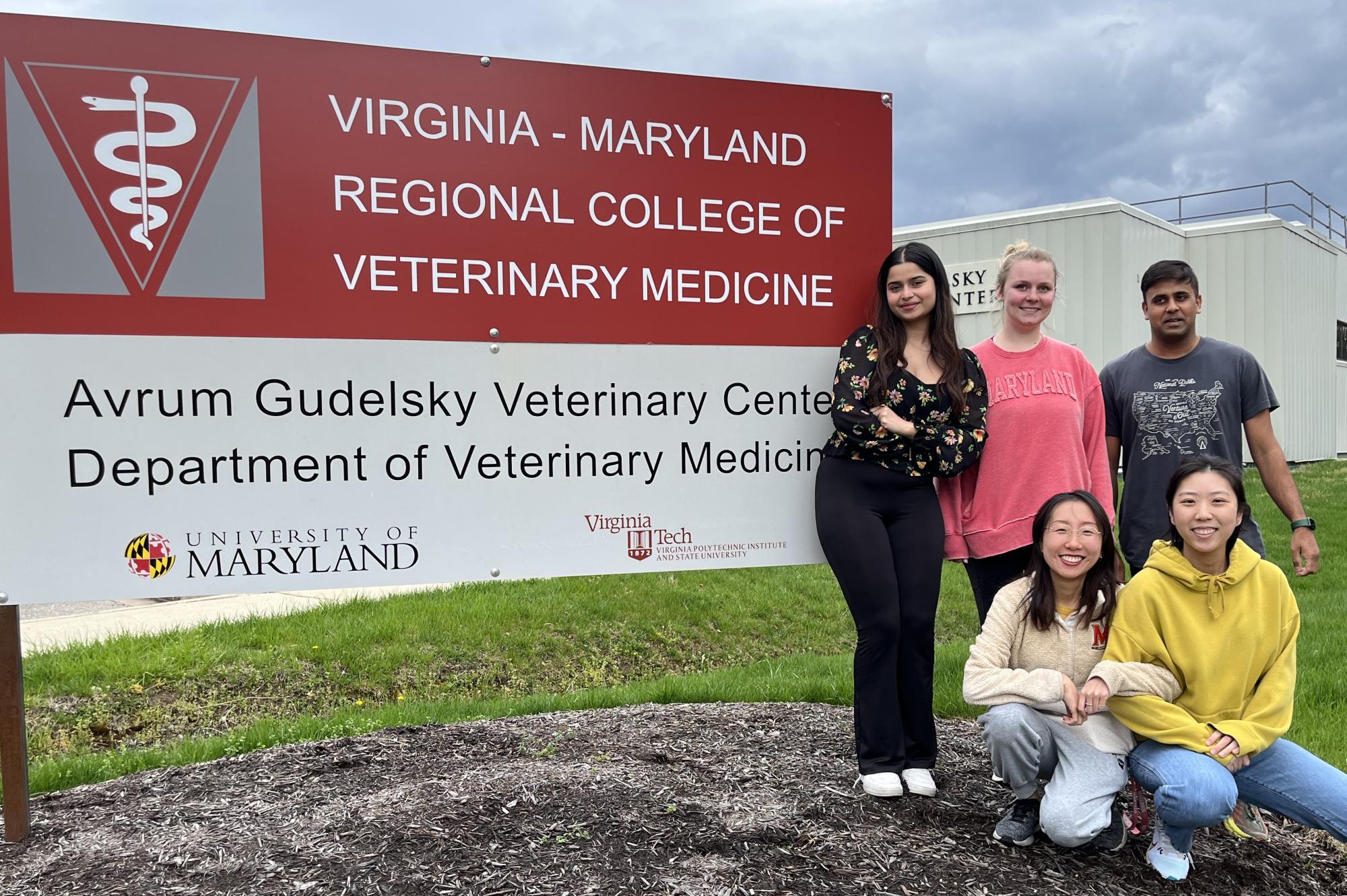 group of people posing infront of vetmed sign